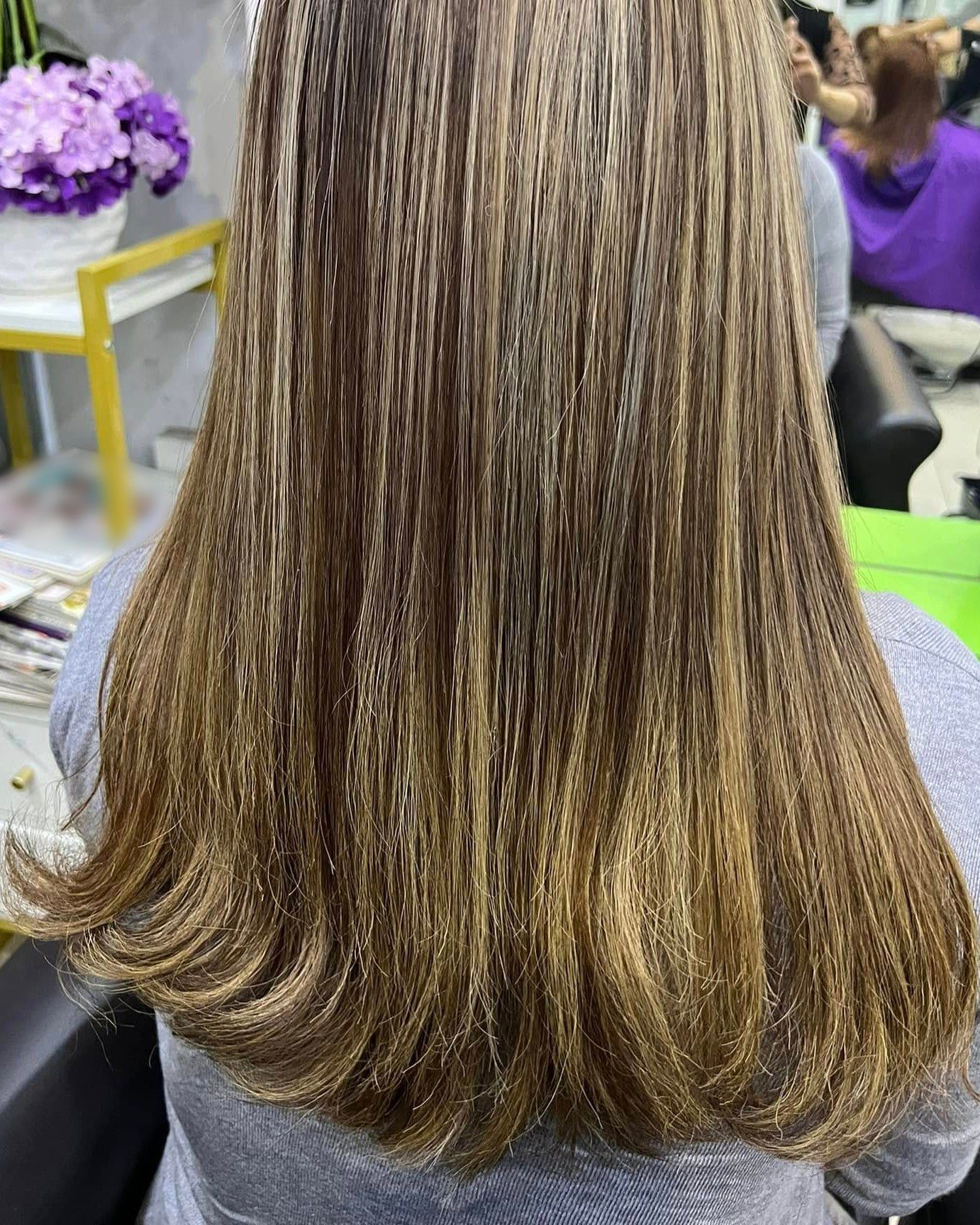 Rambut panjang lurus dengan highlight bronde, campuran perang dan blonde, dilihat dari belakang